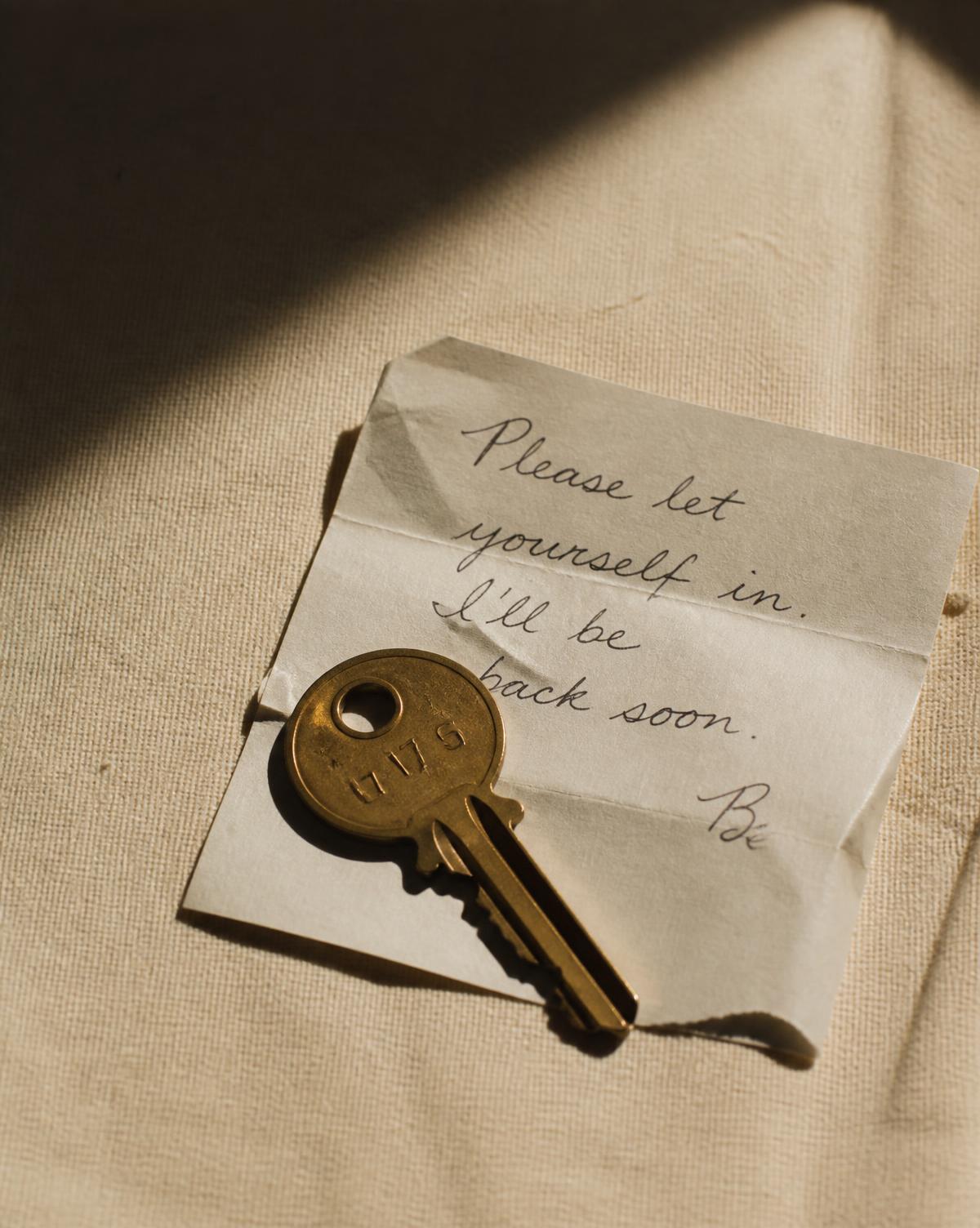 A brass key resting on a folded handwritten note